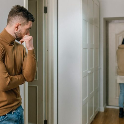A couple experiencing a tense moment as a woman walks out of the apartment.