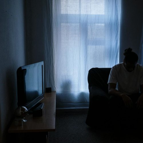 A person sits alone in a dimly lit room, reflecting solitude and moodiness.